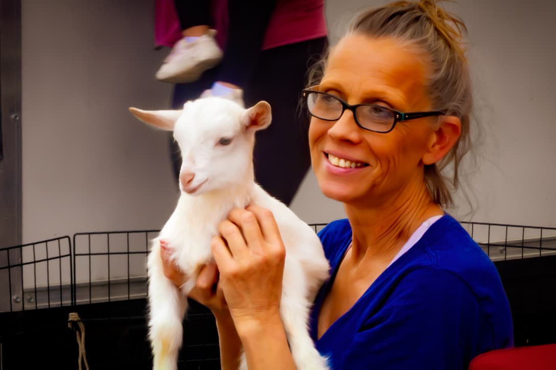 Janie Paslaski smiles while holding a small white goat at the Downtown Bloomington Farmers Market.
