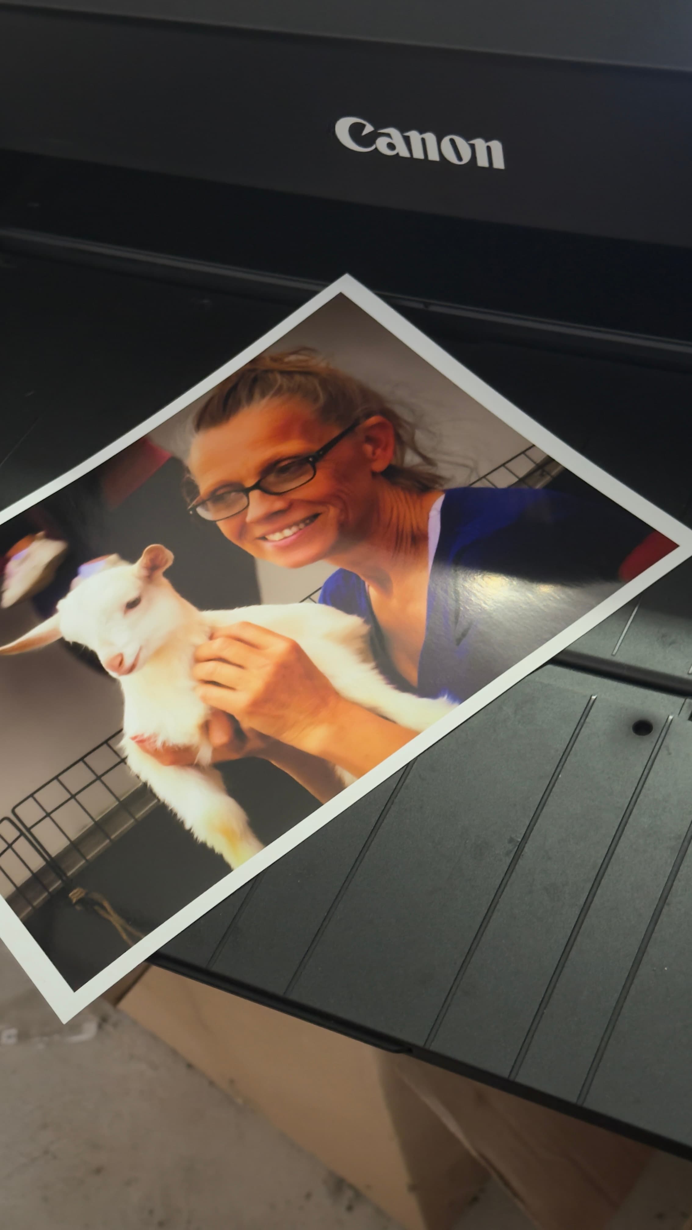 A Canon printer holds a glossy portrait print of Janie Paslaski smiling while holding a white goat.