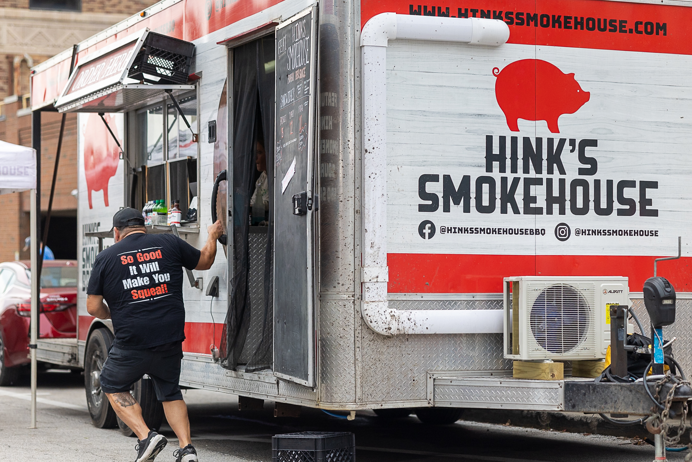 Hink’s Smokehouse food truck at the Downtown Bloomington Farmers’ Market with its large red pig logo and branding visible.