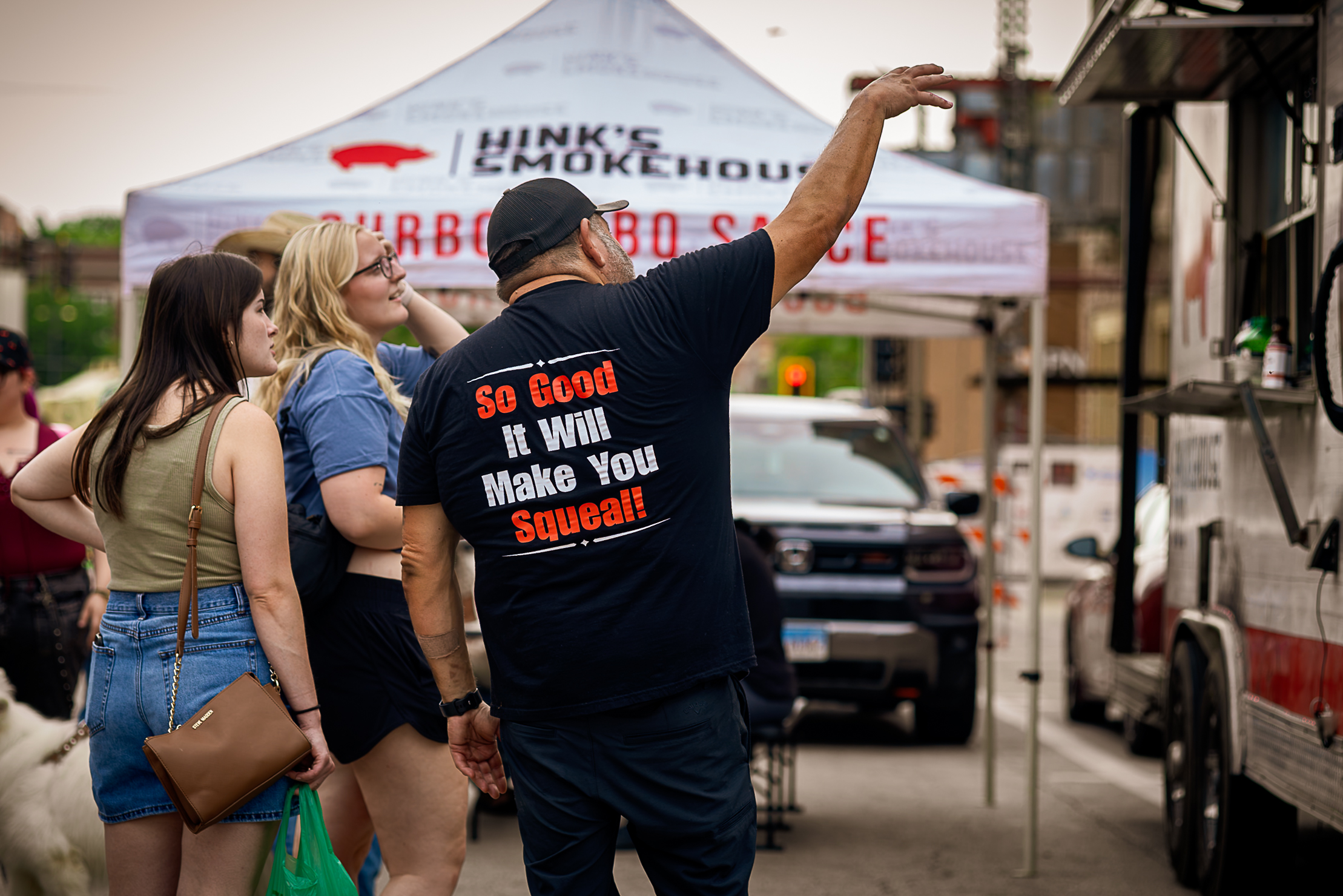 A Hink’s Smokehouse team member talks with customers beside the food truck at the Downtown Bloomington Farmers’ Market.